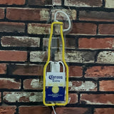 Neon sign in the shape of a Corona Extra beer bottle with a yellow outline and white and green line accents, mounted on a red and white brick wall.