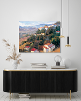 Landscape painting of hillside village with terracotta roofs, green trees, and distant mountains under a cloudy sky, displayed above a modern black sideboard.