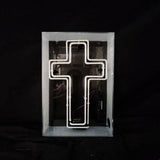 White neon light shaped as a cross inside a rectangular transparent acrylic box, set against a black background.