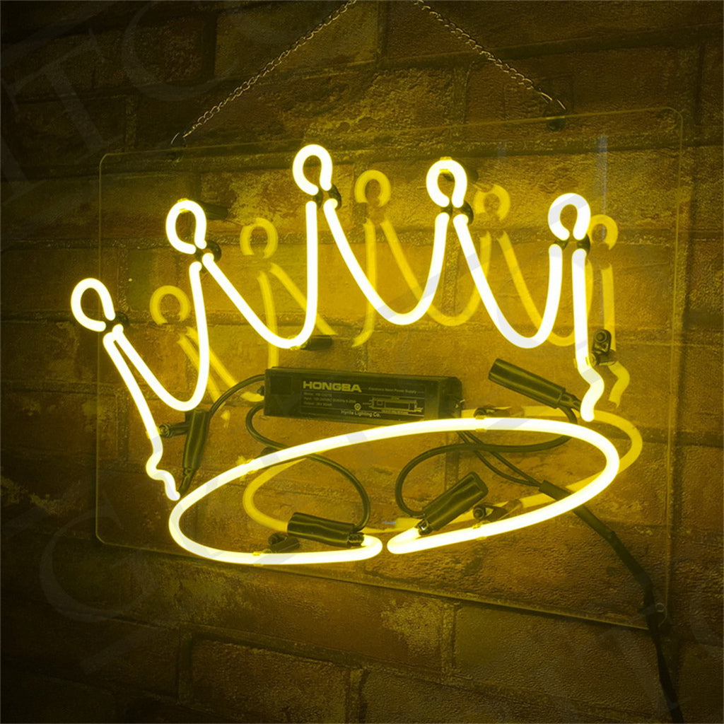 Yellow neon sign shaped like a crown mounted on a clear rectangular panel, hanging against a textured brown wall with visible electrical components behind.