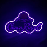 Purple neon light outlining the Crown Royal logo and text on a dark background, with glowing accents highlighting the signature crown shape.