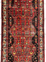 Vintage Persian Hosseinabad runner rug with deep red central geometric medallions and intricate floral motifs, framed by cream and red patterned borders.