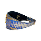 Wide bracelet with blue and gold textured leather and a gold lion head detail, viewed from an angle showing its curved shape and buckle.