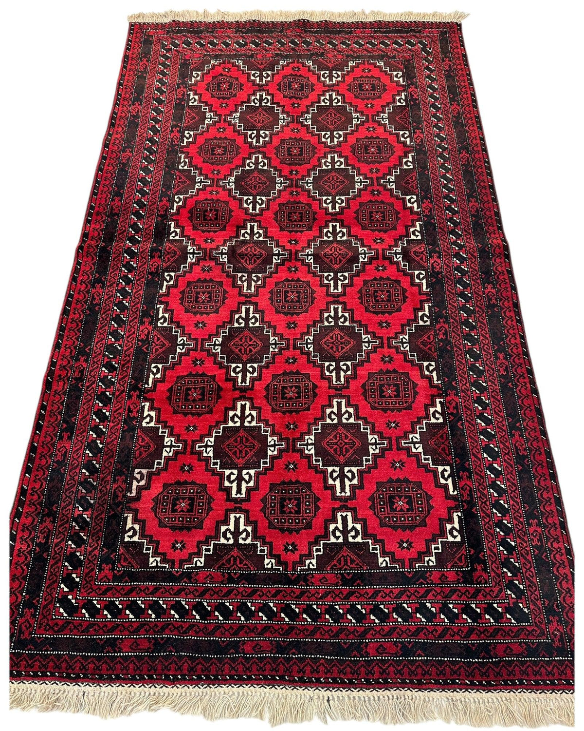 Hand-knotted Afghani Baluch wool rug with a red and black geometric pattern featuring repeated diamond and medallion motifs, bordered by intricate linear designs and white fringes.