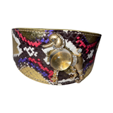 Wide poodle collar with a snakeskin pattern in brown, tan, red, purple, and white, featuring a prominent gold-tone poodle charm with rhinestone accents and a large central gem.