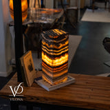 Tangerine Onyx Table Lamp glowing with bright orange upper band and layered natural stone patterns in charcoal and cream
