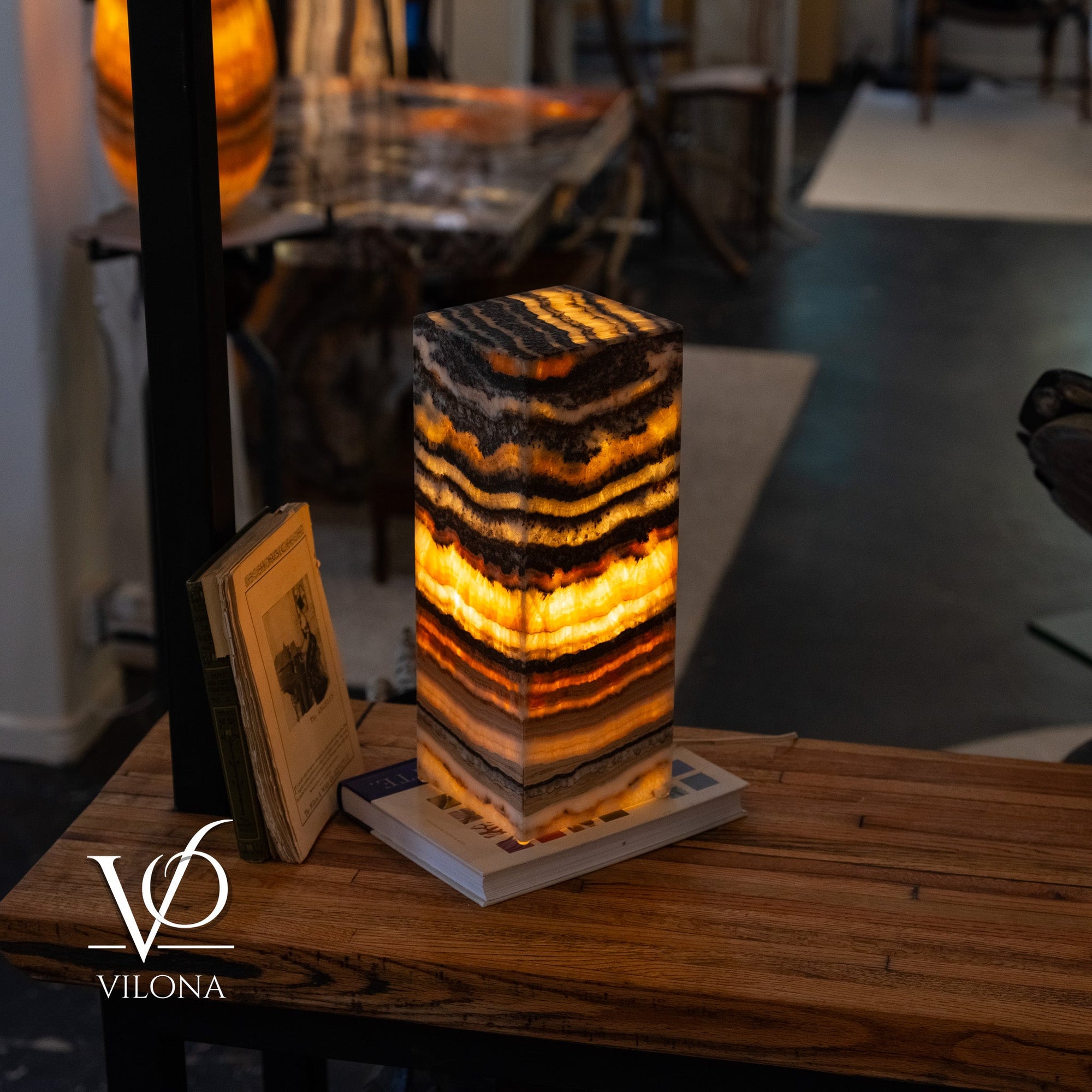 Tangerine Onyx Table Lamp glowing with bright orange upper band and layered natural stone patterns in charcoal and cream
