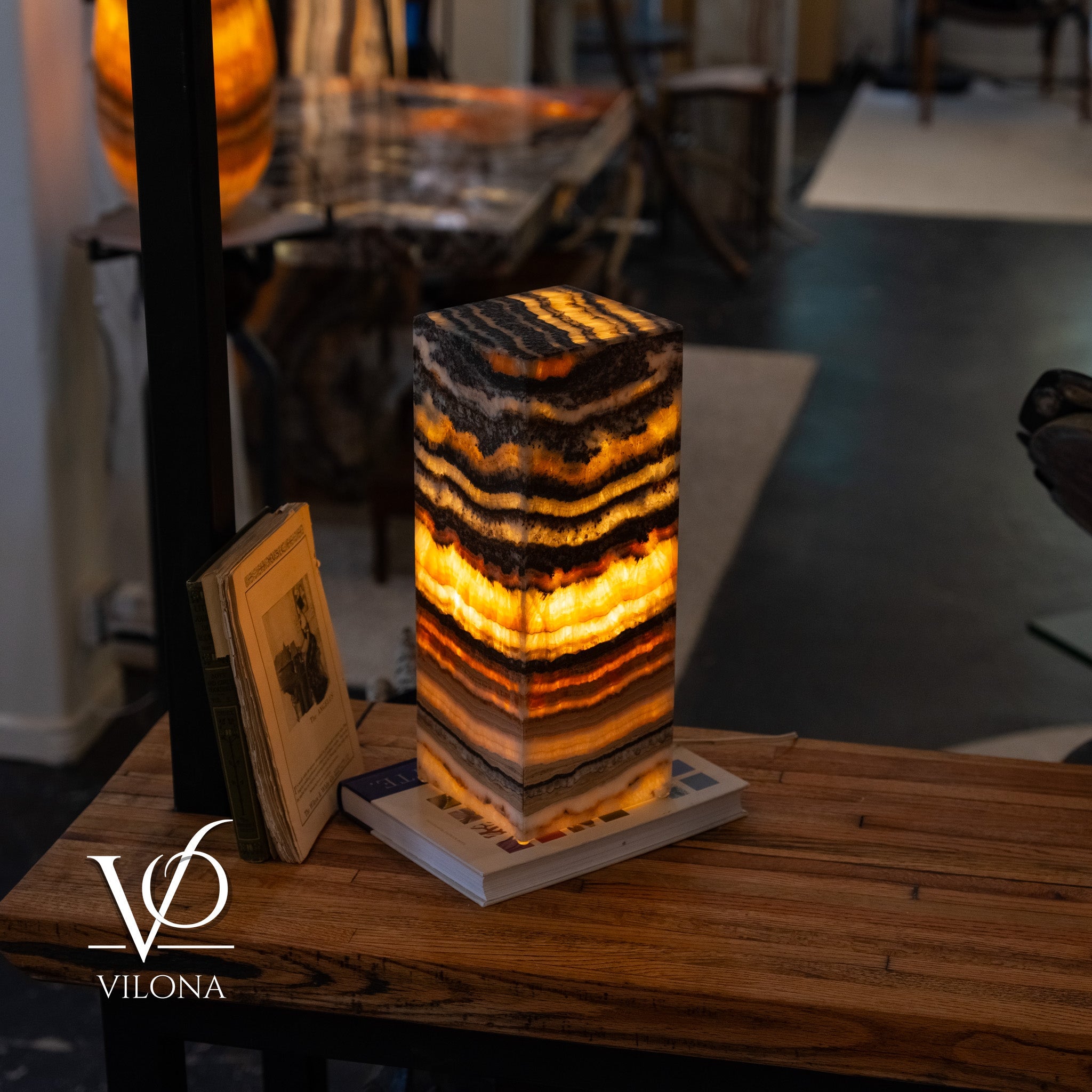 Tangerine Onyx Table Lamp glowing with bright orange upper band and layered natural stone patterns in charcoal and cream