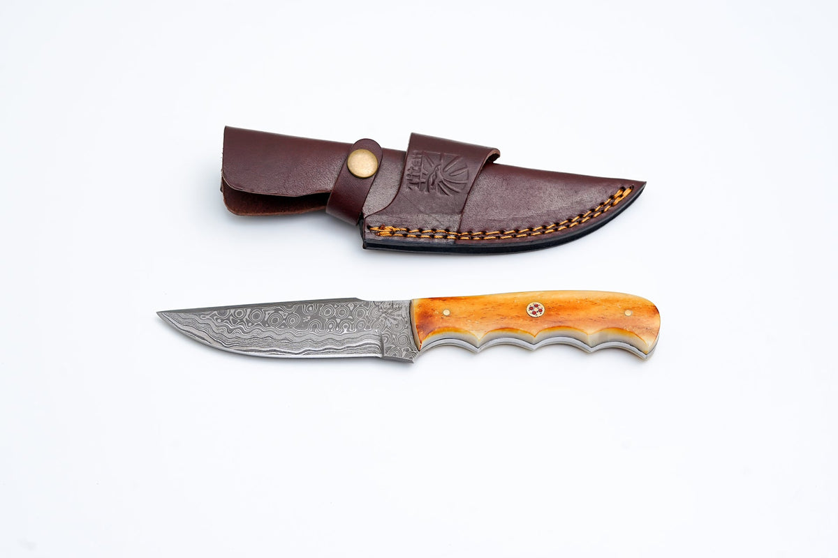 A.5 Damascus steel knife with burnt bone handle scales lying on a black surface