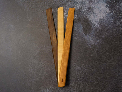 Wooden Spurtle utensil lying on a gray linen cloth near vintage kitchenware