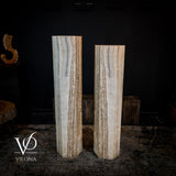 Pair of tall white ice onyx floor lamps with hexagonal shape and layered natural striations, standing side by side against a dark backdrop on a textured floor.