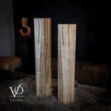 Pair of large white ice onyx floor lamps with vertical natural striations in cream and brown tones, standing on a textured floor against a dark wall.