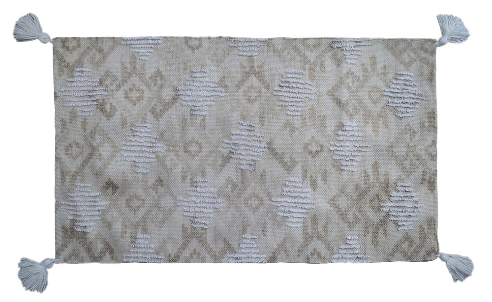 Tufted accent rug in beige tones with corner fringes laid on a tile floor
