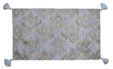 Tufted accent rug in beige tones with corner fringes laid on a tile floor
