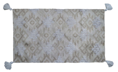 Tufted accent rug in beige tones with corner fringes laid on a tile floor