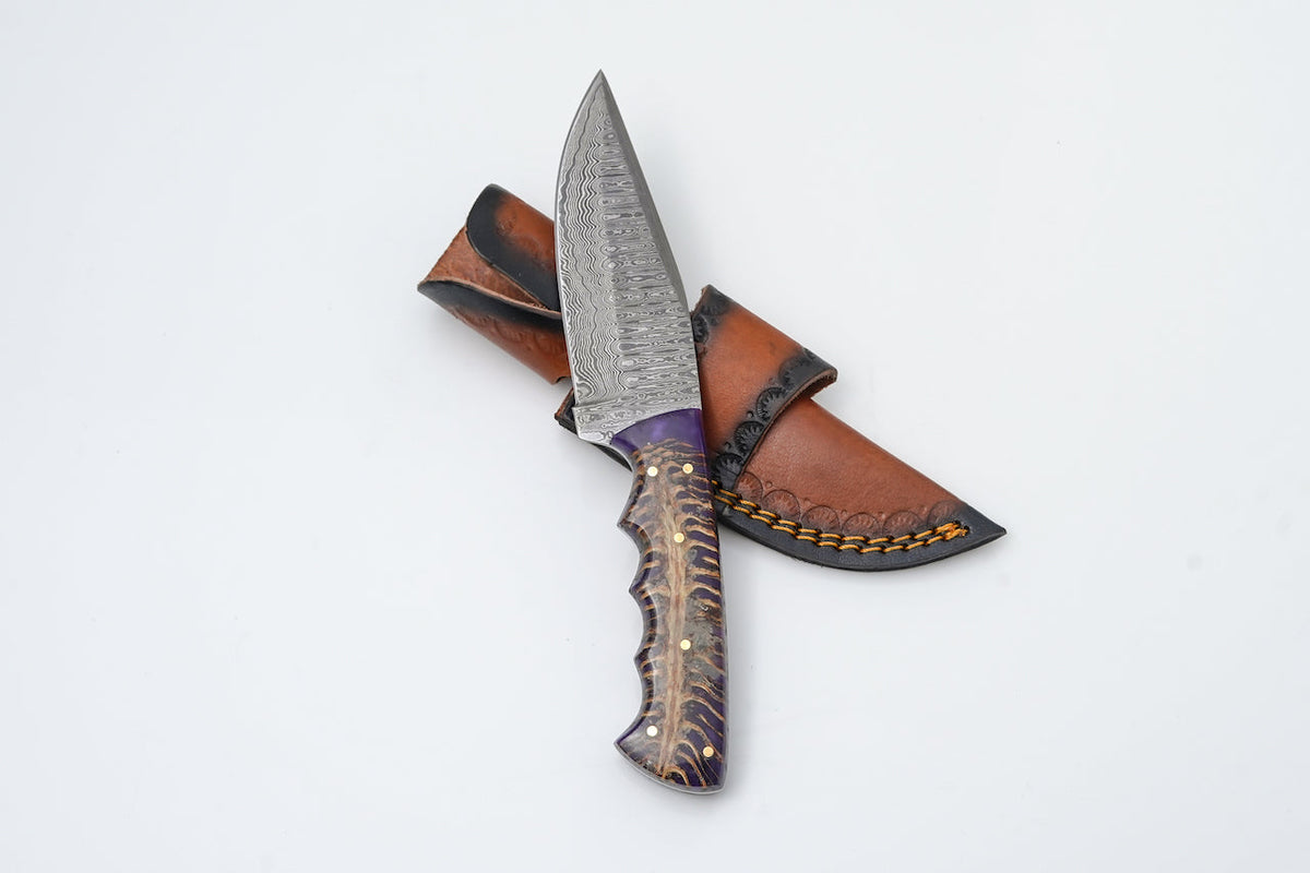Ironfang Damascus Hunter Knife with Damascus steel blade and ergonomic handle next to premium leather sheath