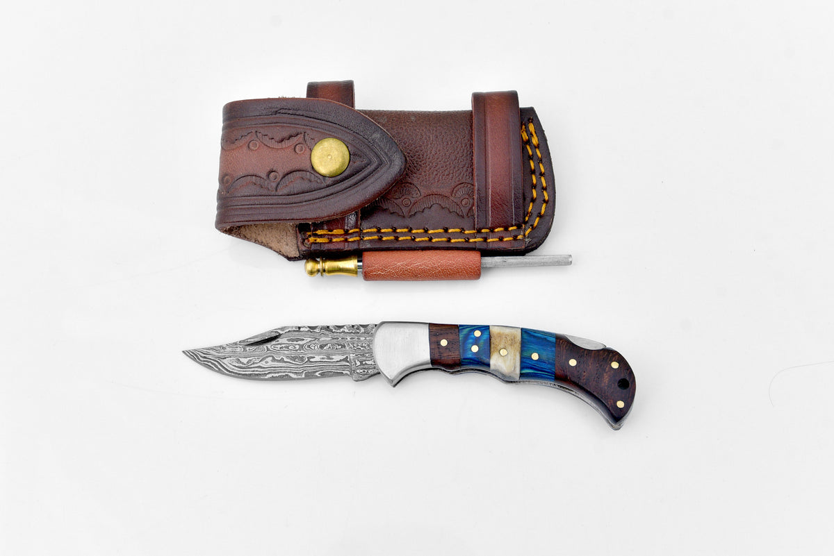 Damascus steel pocket knife Limited Run TF-071 lying open on a flat surface, showing the detailed twisted Damascus steel blade and engraved handle