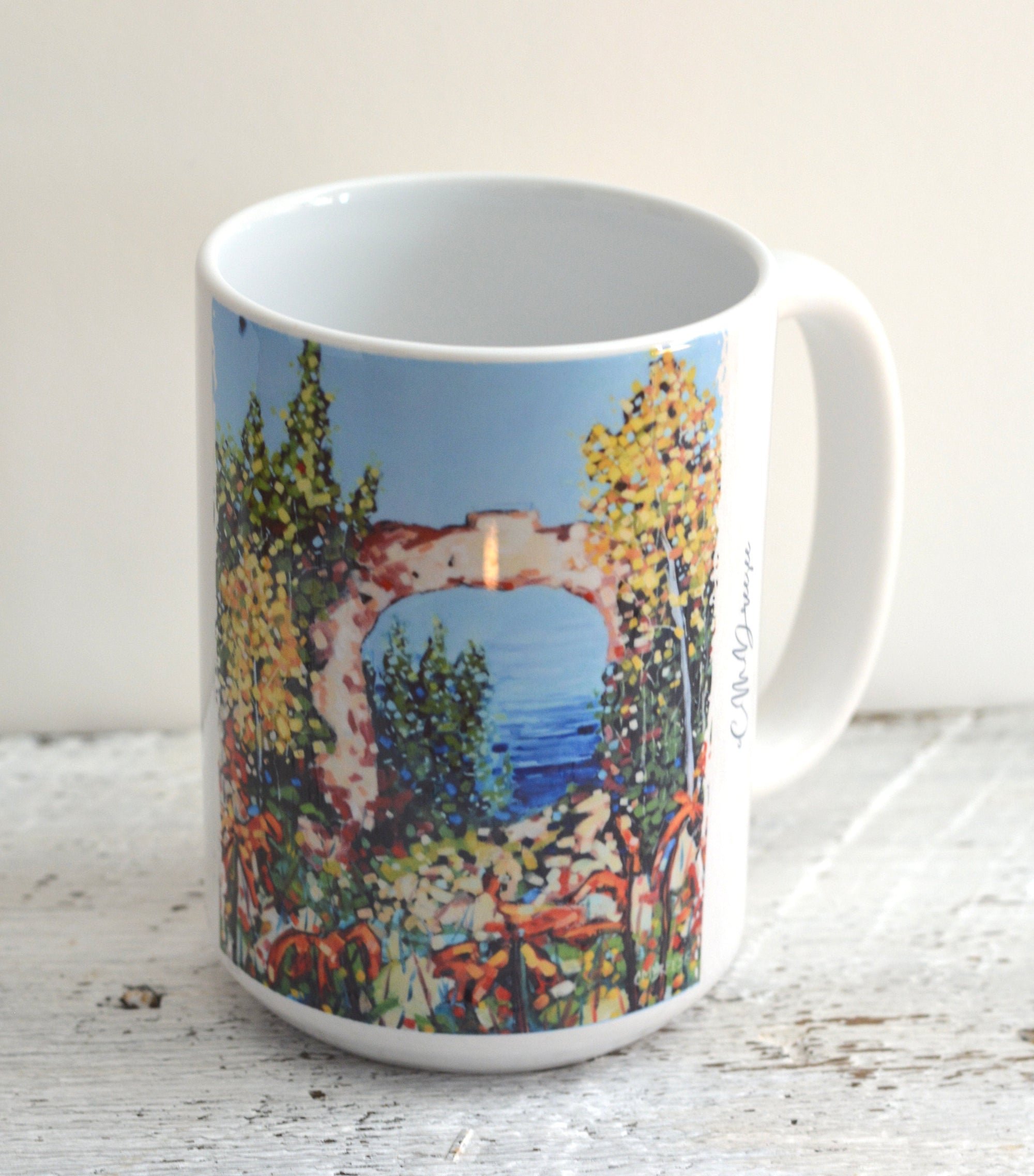 Drinkware collection featuring Arch Rock Mackinac Island design by Christi Dreese, including ceramic mugs and stainless steel tumbler.
