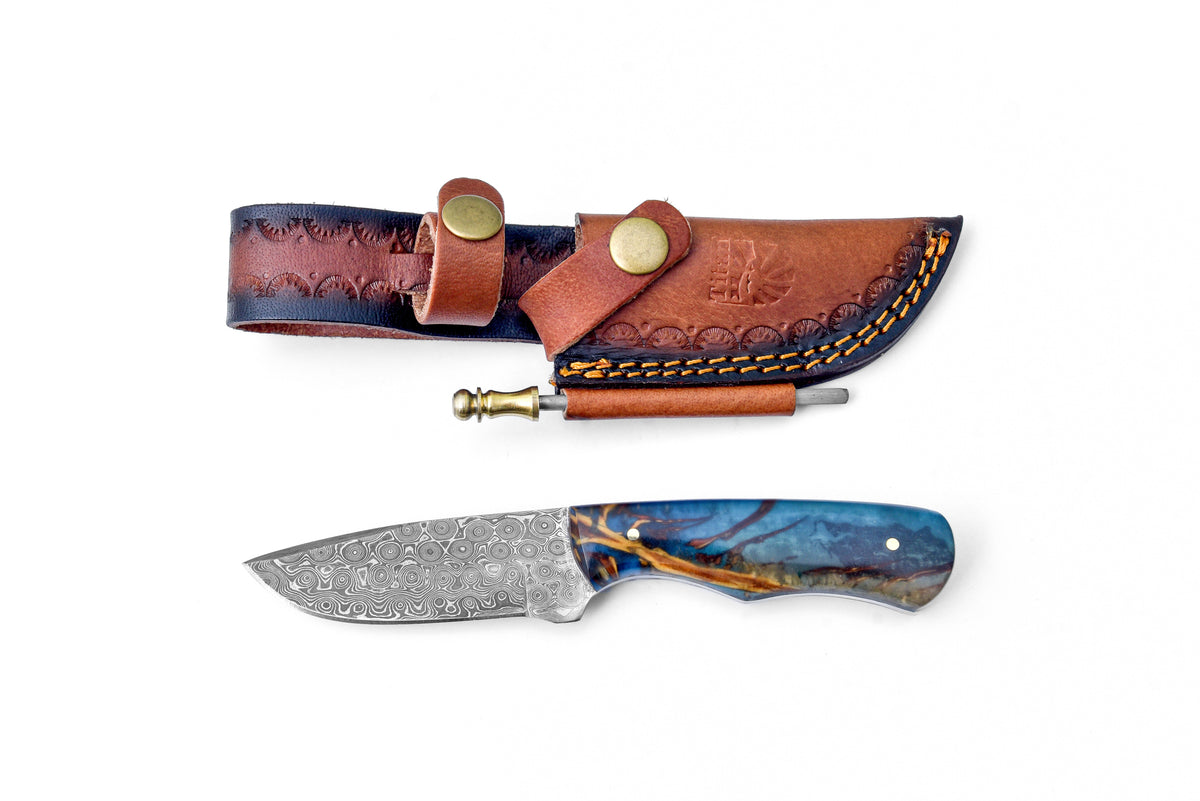 The Forestborn Blade TK-455 fixed blade knife with a stabilized resin handle embedding a real pine cone, shown with leather sheath