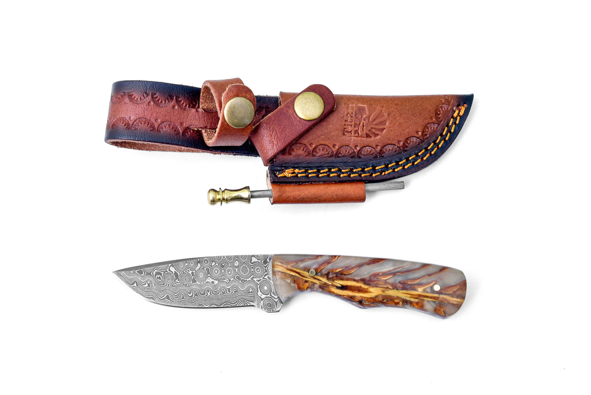 The Barkspire Blade TK-456 knife resting on a wooden surface, featuring a Damascus steel blade and stabilized resin handle with natural wood-grain veining.