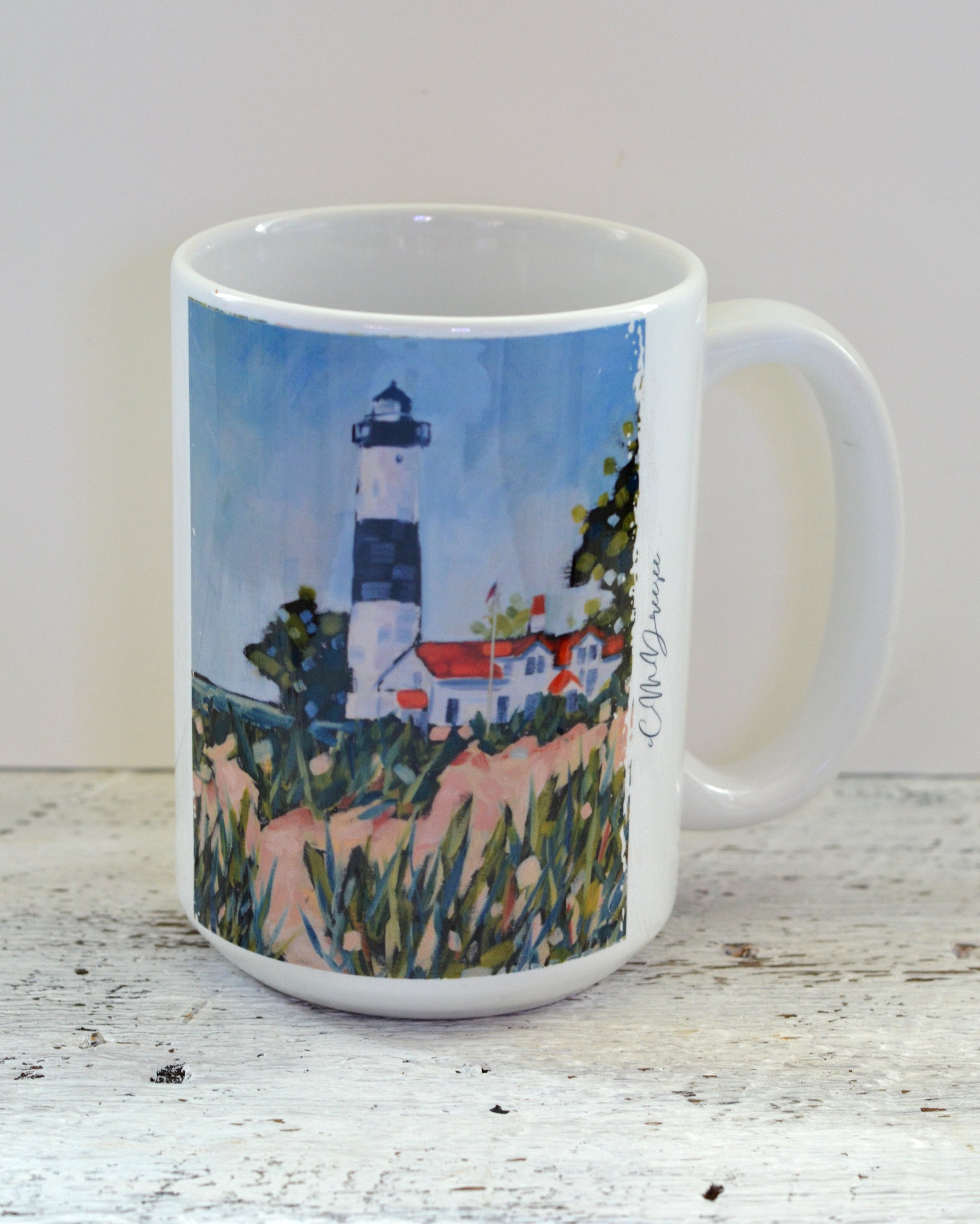 Drinkware pieces featuring Big Sable Point Lighthouse artwork by Christi Dreese, including ceramic mugs and a stainless steel tumbler.