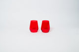 Two faceted, stemless wine glasses in bright cherry red, shown side by side on a white background.
