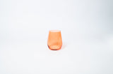Short, translucent orange wine glass with a smooth finish, shown against a white background centered in the frame.