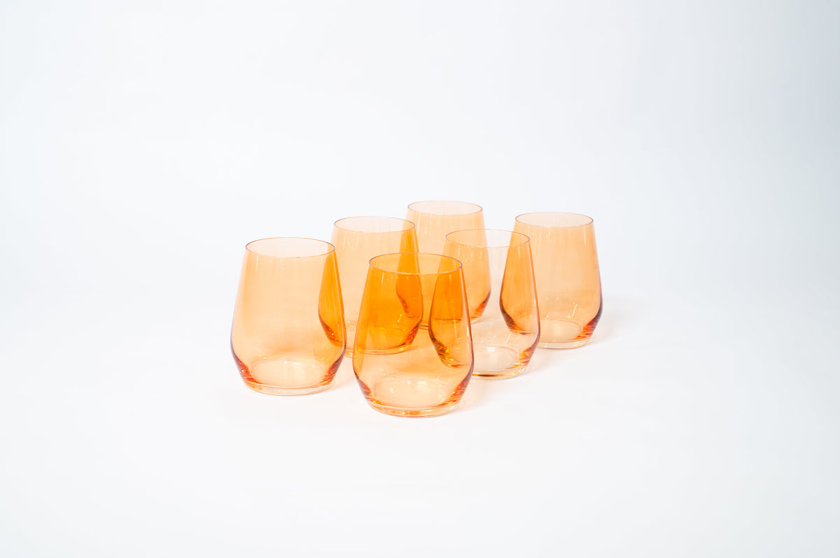 Five stemless wine glasses in translucent orange with gently curved sides, arranged closely on a white background.