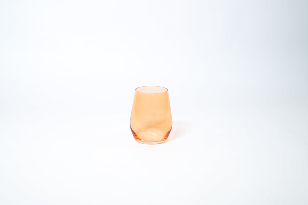 Creamsicle stemless colored wine glass in soft orange on a wooden table
