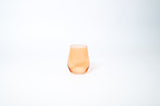 Creamsicle stemless colored wine glass in soft orange on a wooden table