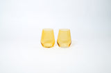Two short, translucent yellow wine glasses with subtle vertical ridges, shown side by side on a white background.