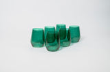 Five emerald green, stemless wine glasses with a smooth, slightly tapered shape grouped on a white background.