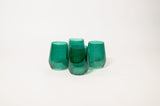Set of four emerald green tinted wine glasses with smooth, rounded sides arranged in a cluster on a white background.