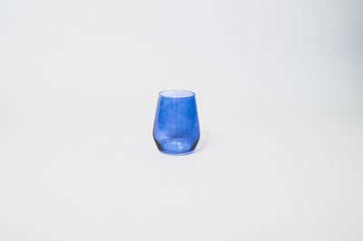 Indigo-go stemless colored wine glass in deep indigo blue on a dark surface