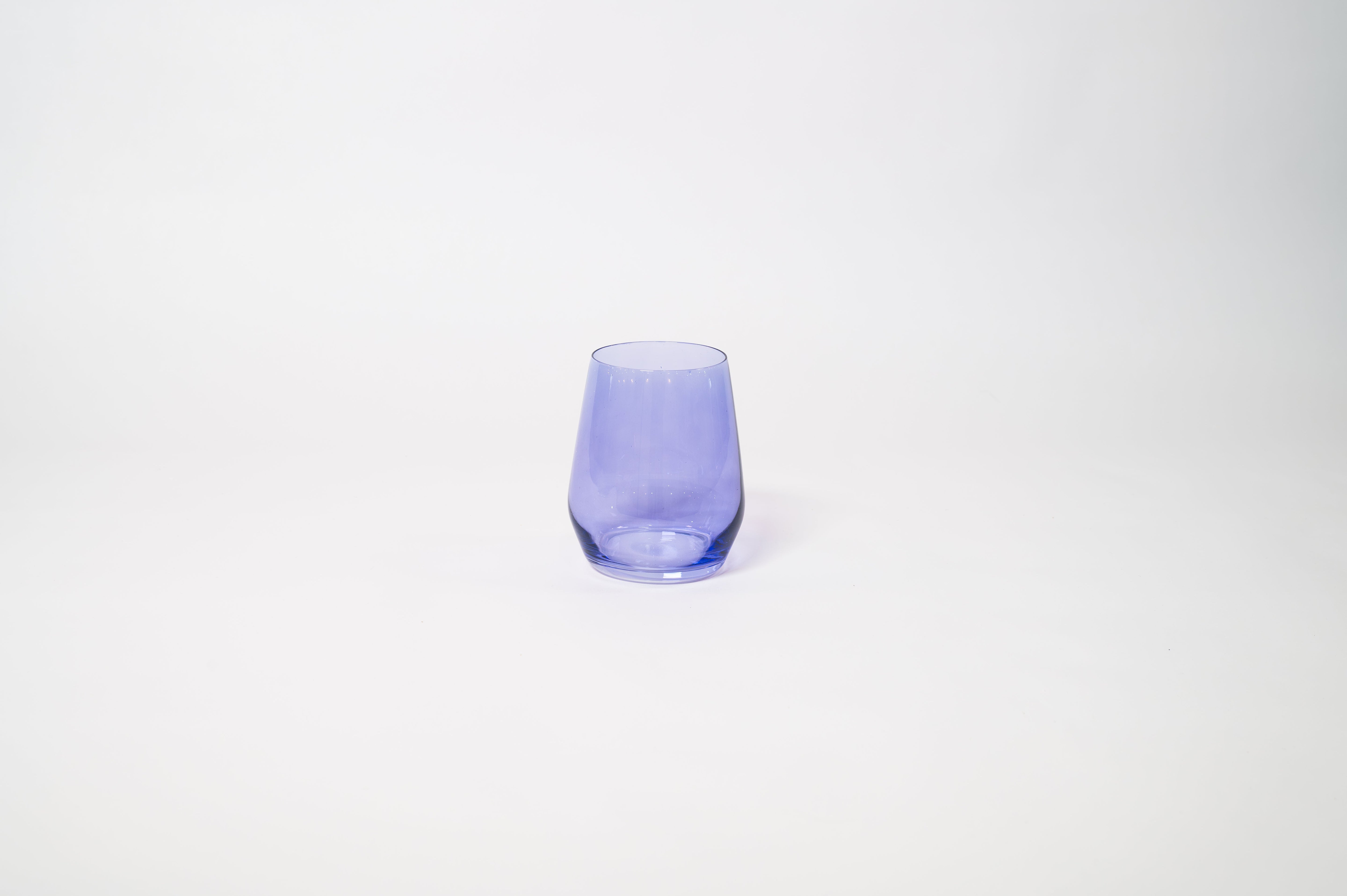 Veri Peri Purple Stemless Colored Wine Glass from glasshauseco, vivid purple hue, on a textured surface with soft light reflections