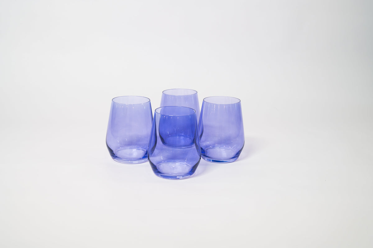 Four stemless wine glasses in translucent periwinkle purple, arranged closely on a white surface against a plain background.