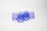 Five stemless wine glasses in varying shades of purple arranged in a loose group on a white surface.