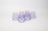 Set of six stemless wine glasses in soft lavender tint arranged in two rows on a white background, showing rounded bases and gently tapered sides.
