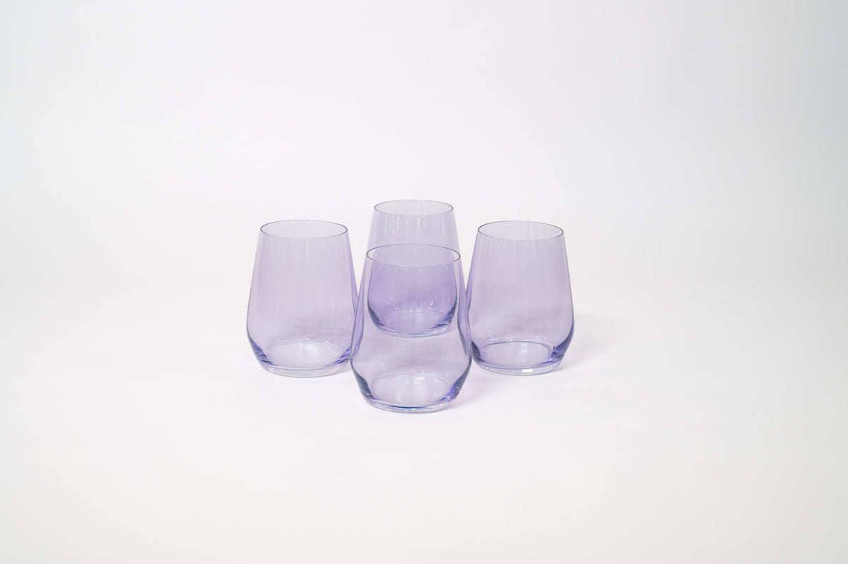 Set of four translucent lavender stemless wine glasses with rounded bodies and slightly tapered tops arranged in a group on a white background.