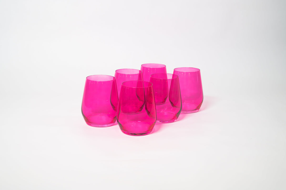 Set of six hot pink stemless wine glasses with a simple, rounded shape arranged on a white surface, showing their translucent color and smooth texture.