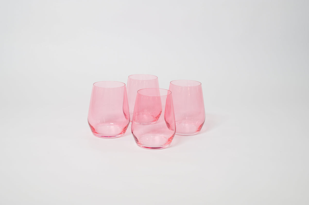 Four stemless wine glasses in translucent bubblegum pink, arranged in a loose cluster on a white surface with soft shadows.