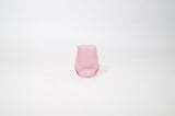 Bubblegum Pink - Stemless Colored Wine Glass by GlassHauseCo on a wooden table with warm, natural light