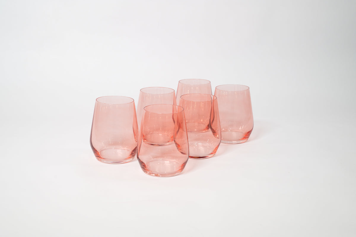 Six translucent pink stemless wine glasses arranged in two rows on a white background, each with a gently curved shape and smooth rims.