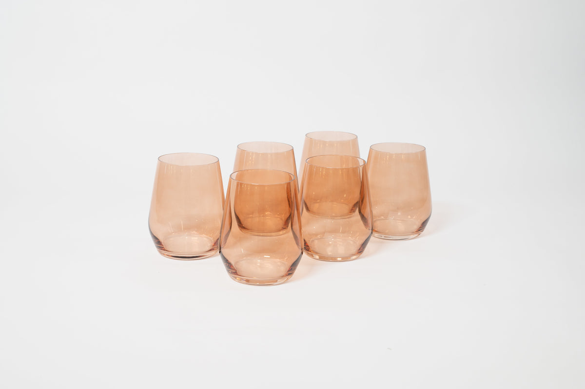 Five stemless wine glasses in a translucent warm amber color, arranged in a slight arc on a white background.