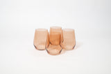 Four stemless wine glasses in a warm brown sugar tint, each with subtle rounded and slightly tapered forms, arranged closely on a white background.