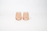 Two stemless brown-colored wine glasses with a smooth, slightly tapered shape set side by side on a white background.