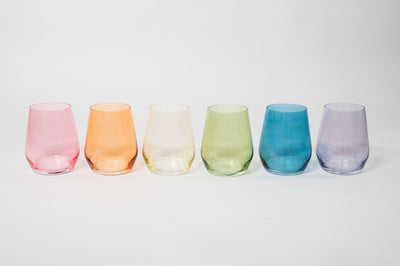Two pastel tone wine glasses on a wooden surface with natural light