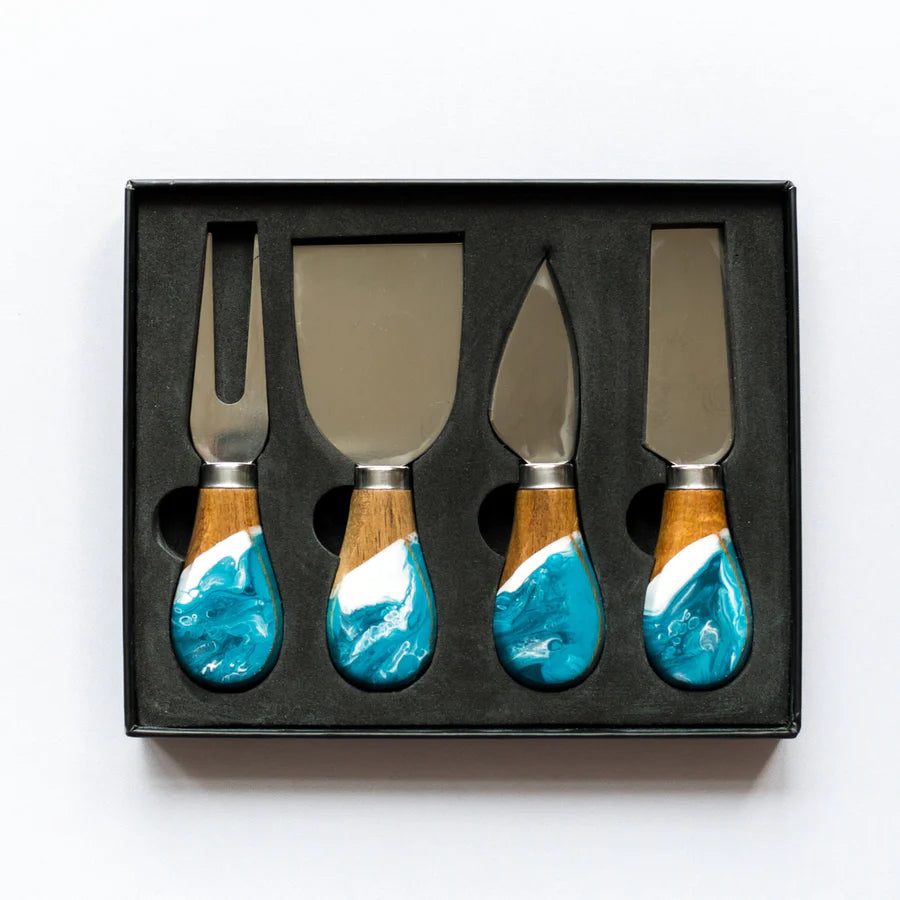 Set of four resin cheese knives with turquoise and wood handles in a black box on a white background