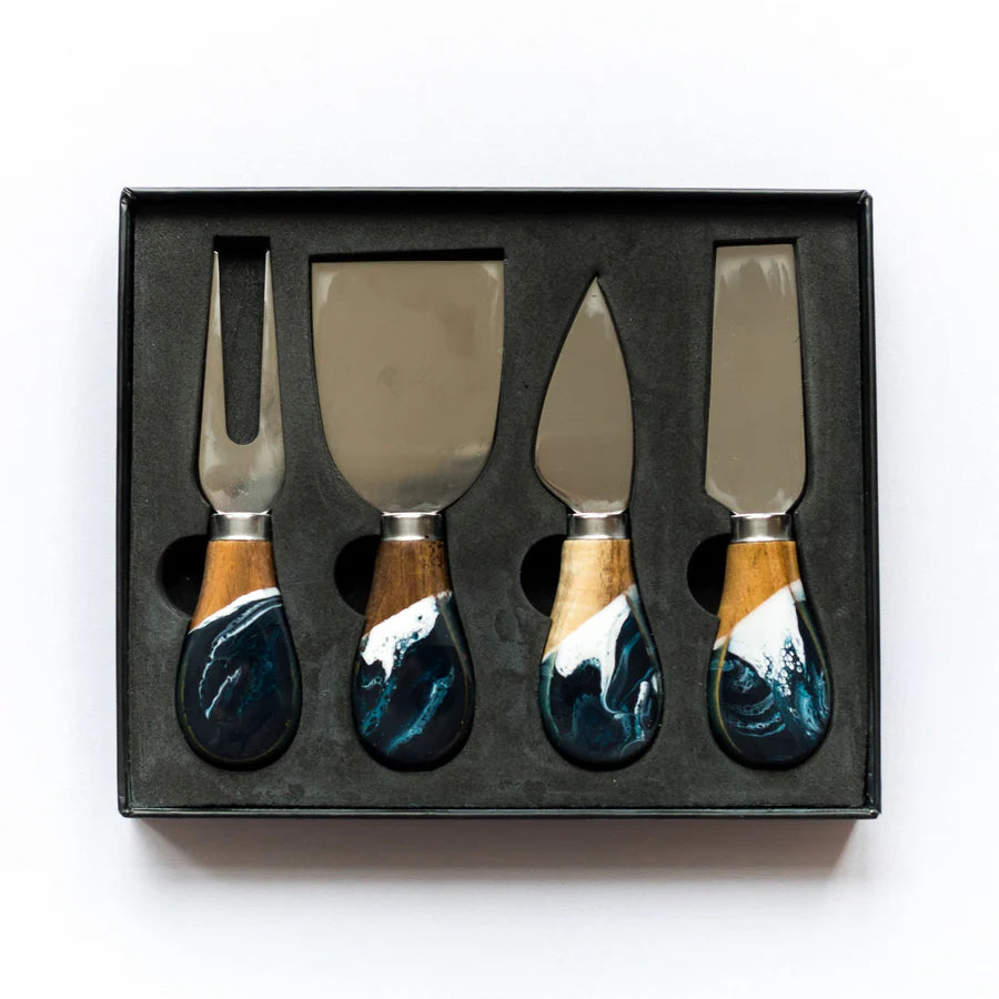 Set of four resin cheese knives with wooden handles in a black box on a white background