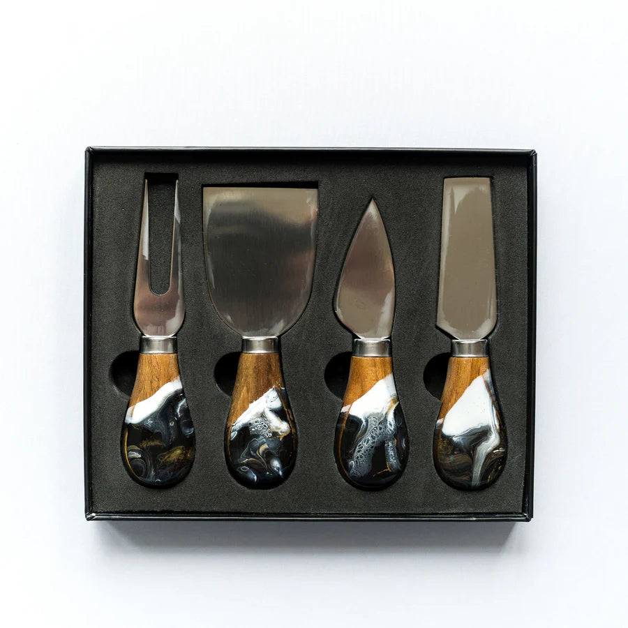 Set of four resin cheese knives with wooden handles in a black box on a white background